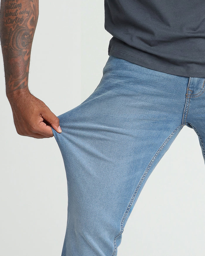 Person wearing light indigo denim jeans with a dark navy shirt, showing the fit through the thigh and hip area.