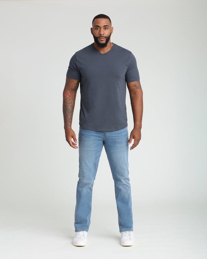 Man wearing light indigo v-neck t-shirt and light blue athletic fit jeans with white sneakers.