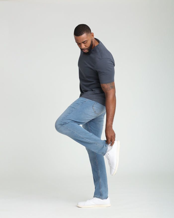 Man wearing light indigo athletic fit jeans with dark gray t-shirt and white sneakers.