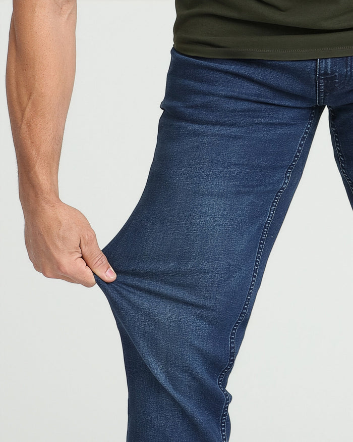 Man wearing dark blue denim jeans with athletic fit and olive green shirt, showing fit and fabric detail.