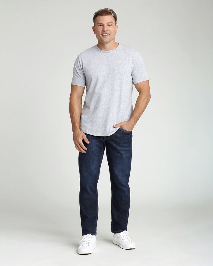 Man wearing light gray short-sleeve t-shirt and dark blue athletic fit jeans with white sneakers.