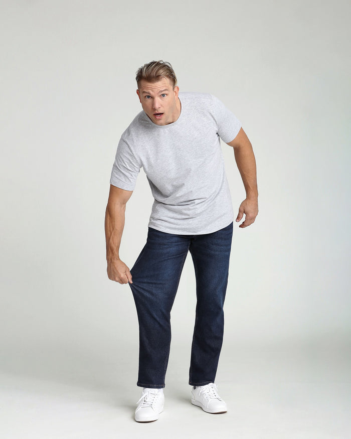 Man wearing light gray t-shirt and dark blue athletic fit jeans with white sneakers.