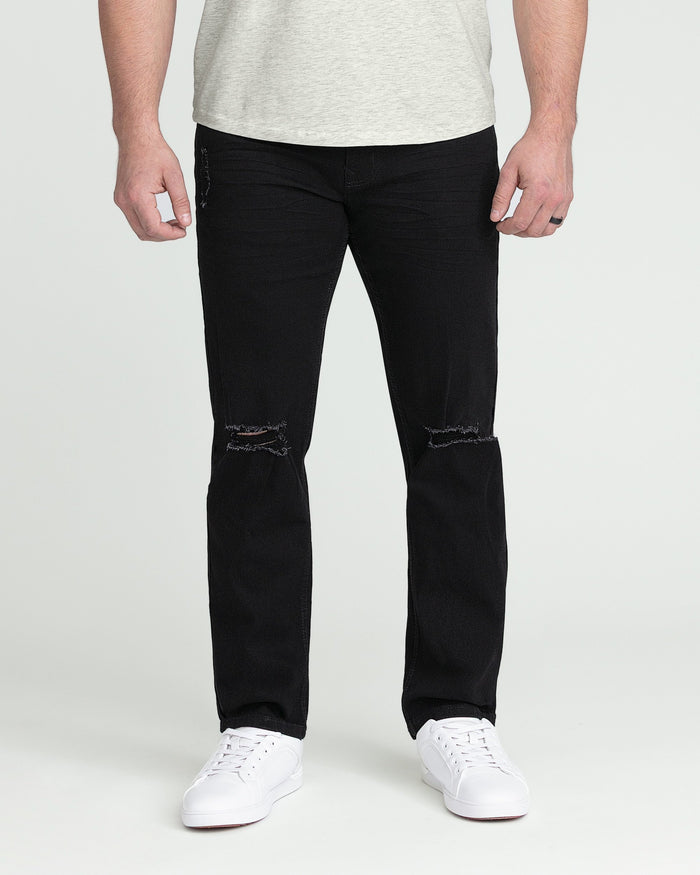 Black athletic fit jeans with ripped knees and raw hem, worn with white sneakers.
