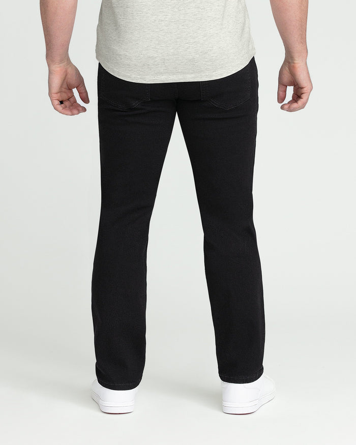 Black athletic fit jeans with ripped thigh detail, worn with gray t-shirt and white sneakers.