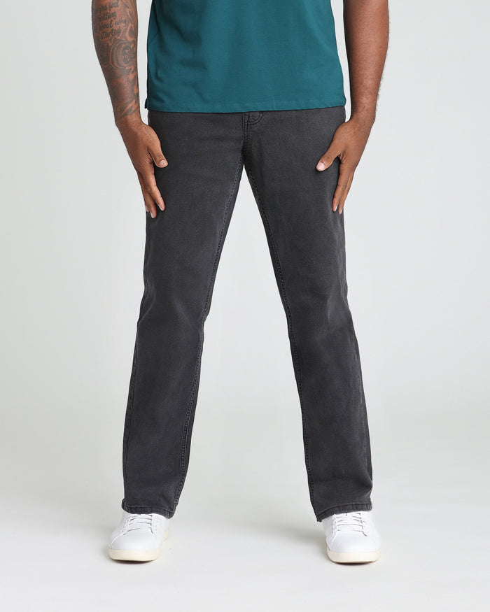 Man wearing faded black athletic fit jeans with teal t-shirt and white sneakers.