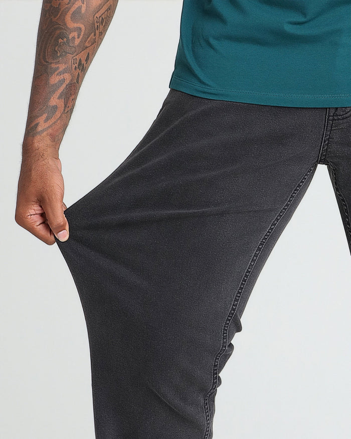 Man wearing faded black athletic fit jeans with teal shirt, showing fabric texture and fit at thigh.