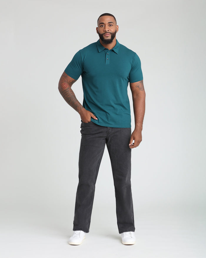 Man wearing teal polo shirt with collar and buttons paired with faded black athletic fit jeans.