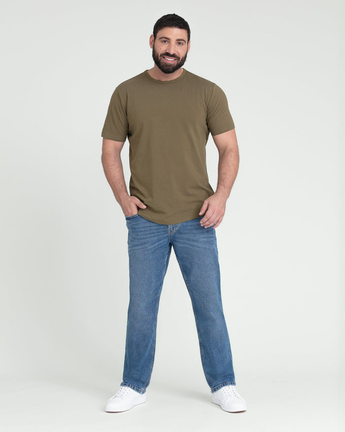 Man wearing olive-green short-sleeve t-shirt with medium blue athletic fit jeans and white sneakers.