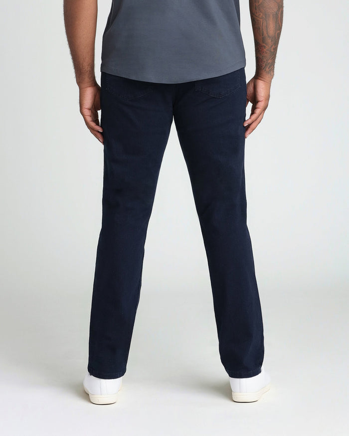Man wearing dark blue athletic fit jeans and gray-blue t-shirt, shown from behind.