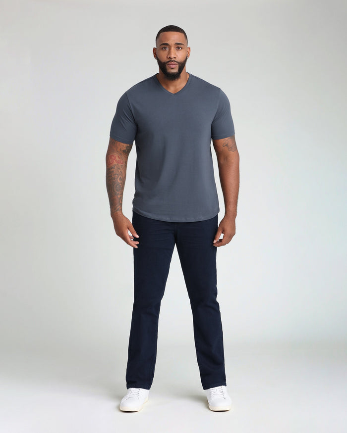 Man wearing deep blue v-neck t-shirt with dark navy pants and white sneakers.