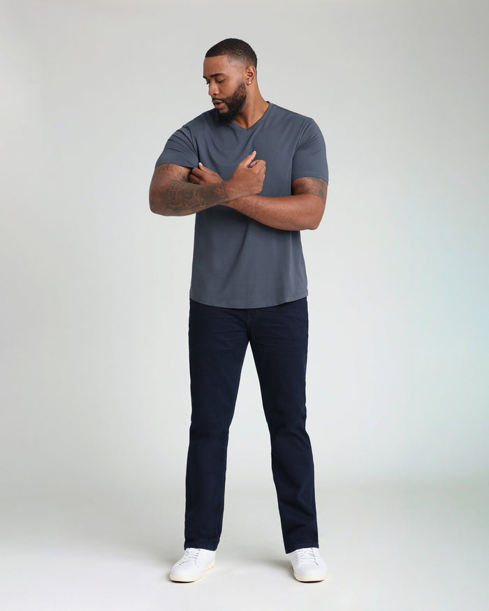 Man wearing deep blue v-neck short-sleeve t-shirt with navy pants and white sneakers.
