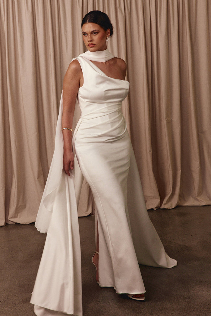 Woman wearing a white off-shoulder gown with a cape