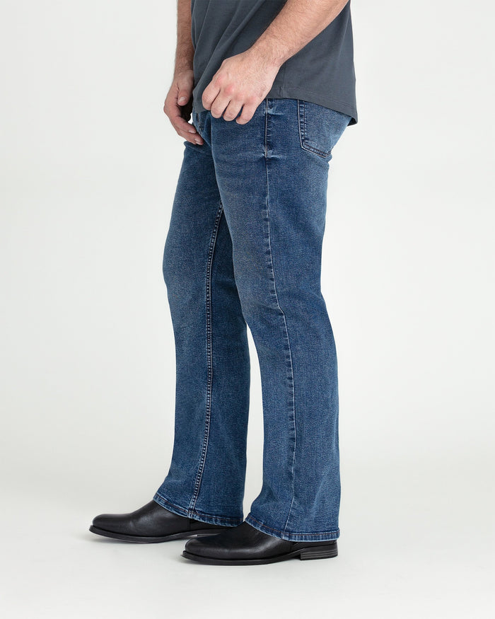 Medium blue bootcut jeans with flared hem, worn with gray shirt and black boots.