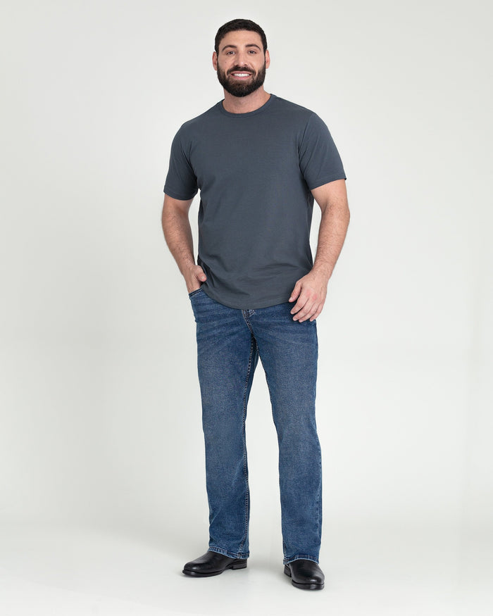Man wearing charcoal t-shirt and medium blue bootcut jeans with black shoes.