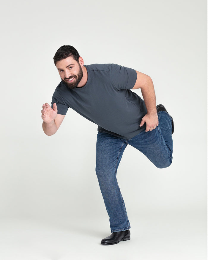 Medium blue bootcut jeans with a flared leg opening, shown on a male model wearing a dark gray t-shirt.
