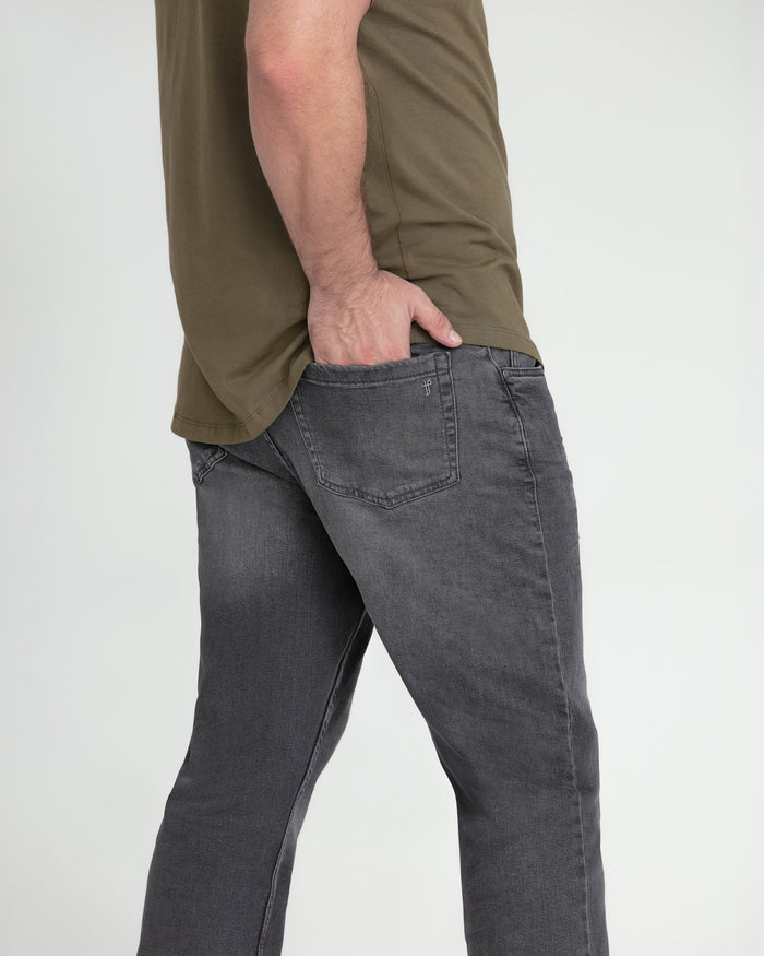 Grey bootcut jeans with five-pocket styling shown on model wearing olive shirt.