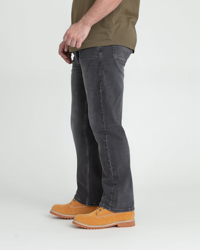 Grey bootcut jeans with visible stitching worn with tan work boots.