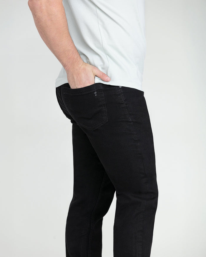 Black bootcut jeans with visible stitching on back pocket, worn with white shirt.