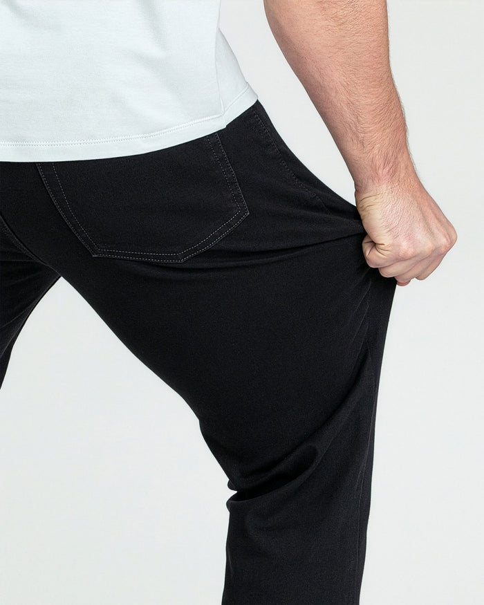 Black bootcut jeans with stitched pocket details shown on model's leg.