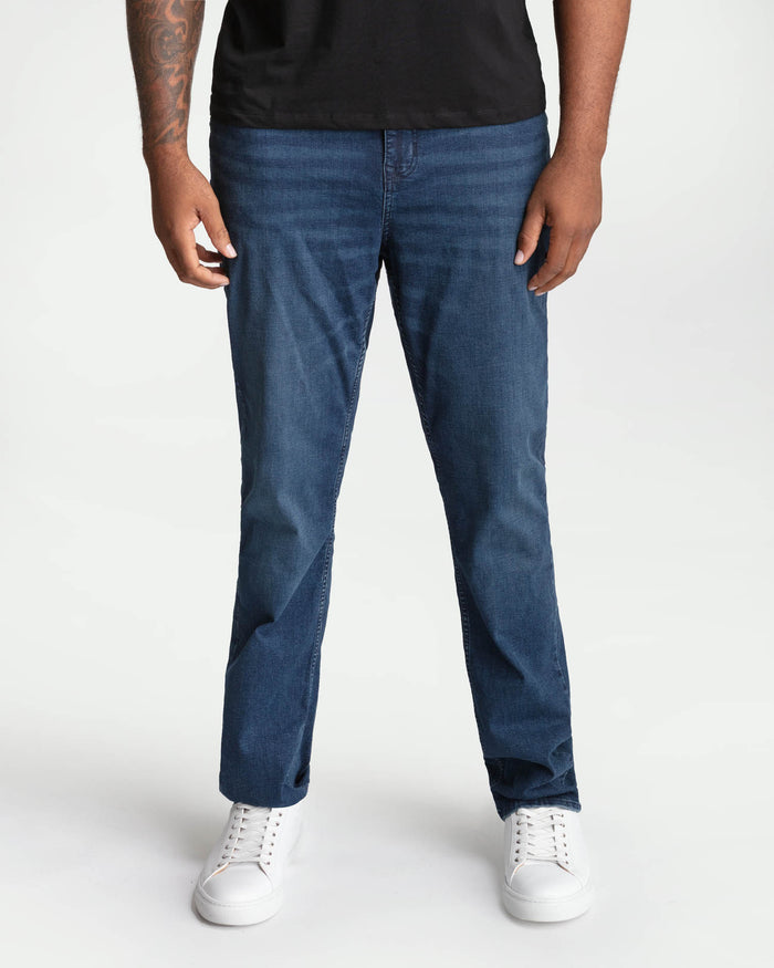 Man wearing midnight blue bootcut jeans with a black shirt and white sneakers.