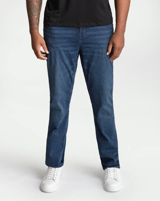 Man wearing midnight blue bootcut jeans with a black shirt and white sneakers.