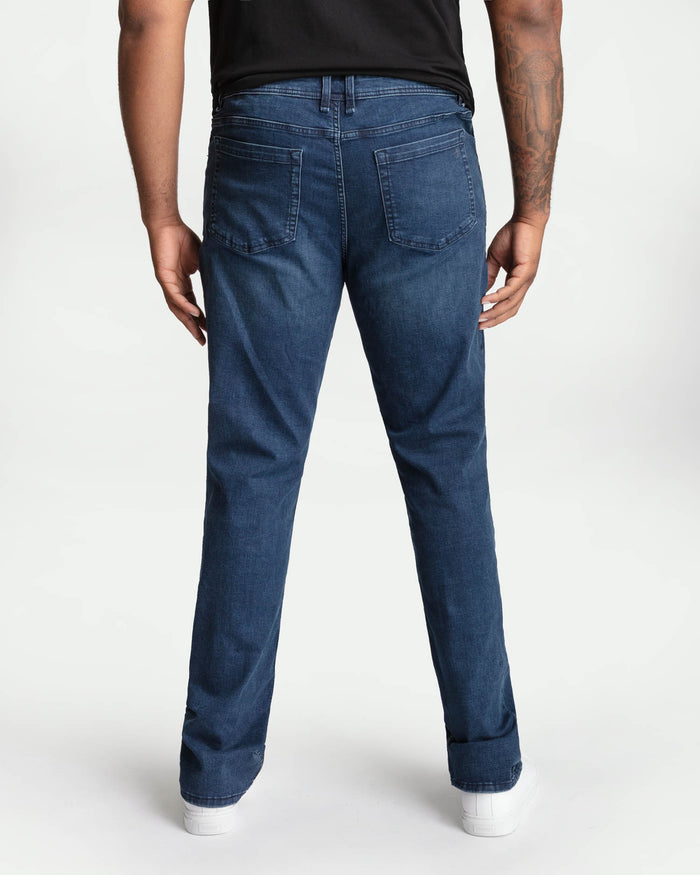Man wearing dark blue bootcut jeans with black t-shirt, shown from back.