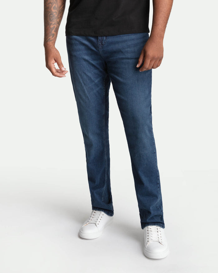 Man wearing midnight blue bootcut jeans and black t-shirt with white sneakers.