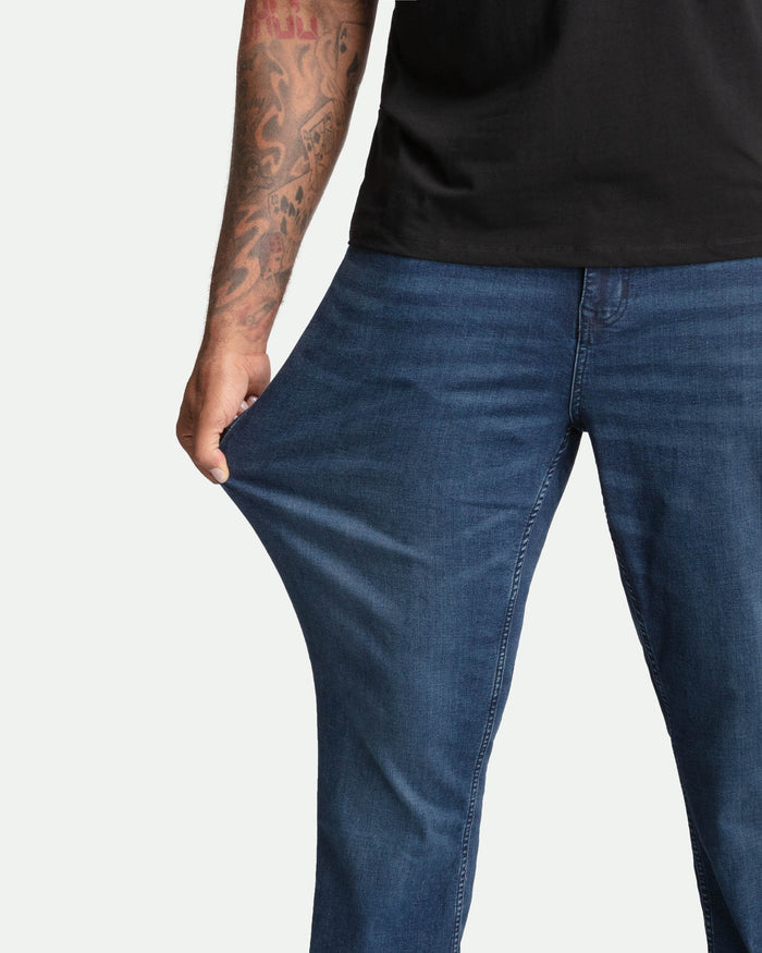 Midnight blue bootcut jeans on model with black shirt, showing leg and waistband fit.