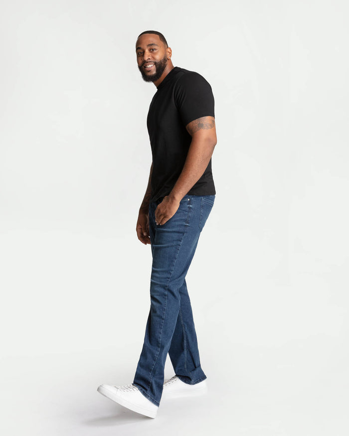 Man wearing midnight blue bootcut jeans with black t-shirt and white sneakers.