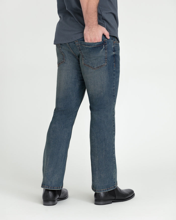 Tinted bootcut jeans with classic five-pocket styling, shown on model wearing black boots.