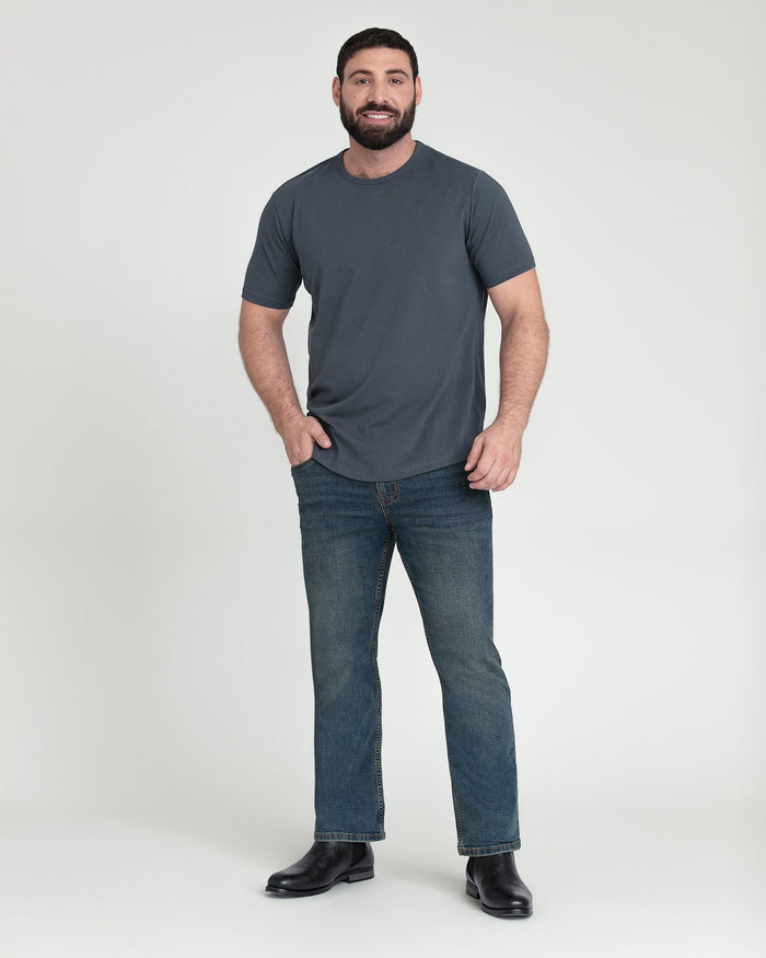 Man wearing charcoal t-shirt and tinted bootcut cowboy jeans with black boots.