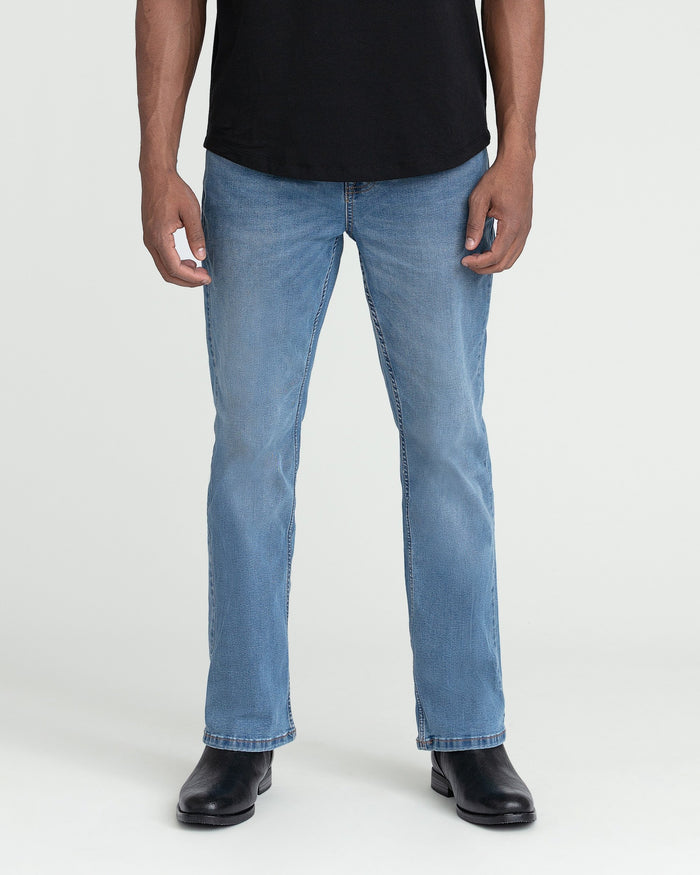Light indigo bootcut jeans on male model wearing black shirt and black boots.