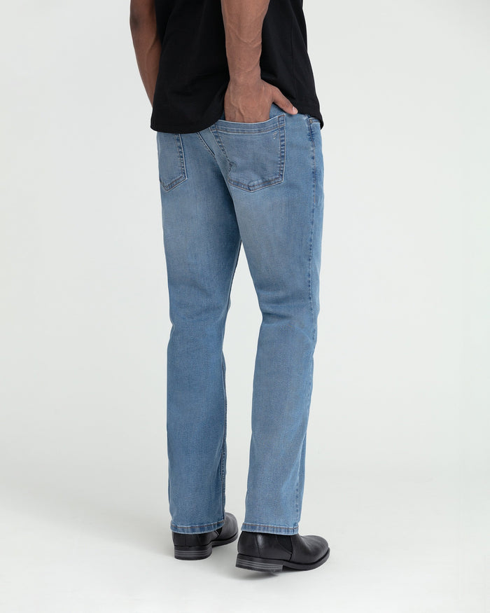 Light indigo bootcut jeans with back pocket detail, shown from behind on model wearing black shirt and black boots.