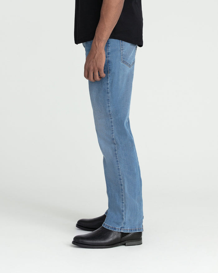 Light indigo bootcut jeans with flared hem, shown on model wearing black shirt and black boots.
