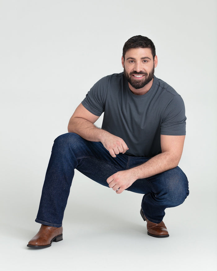 Dark blue bootcut jeans styled with gray t-shirt and brown leather boots on model.