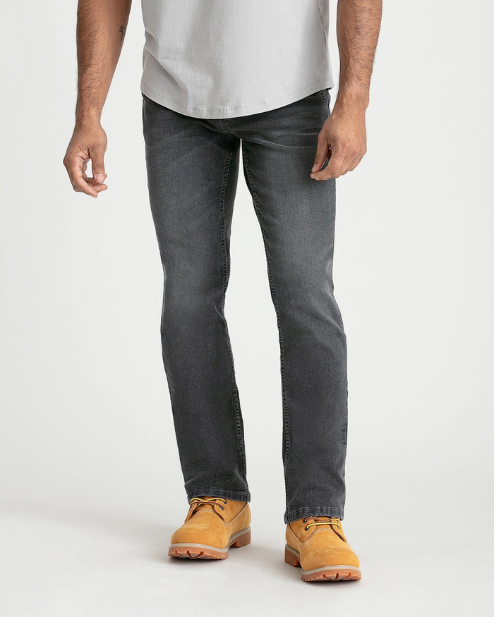 Man wearing grey bootcut jeans with white t-shirt and tan work boots.