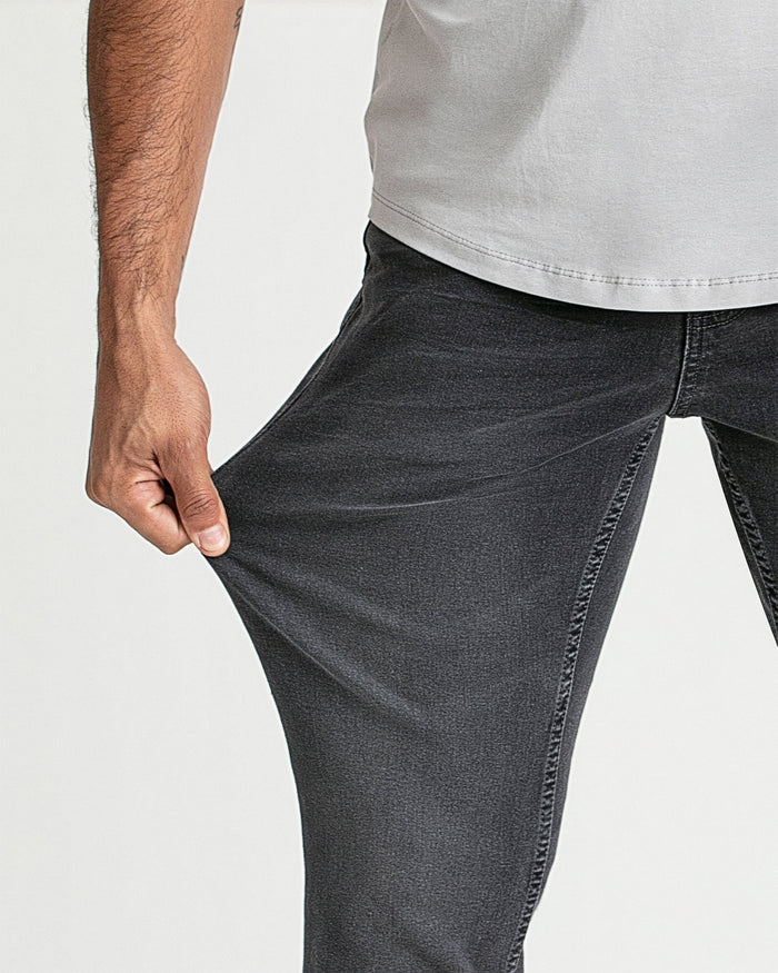 Man wearing grey bootcut jeans with white t-shirt, showing fit at thigh and leg.