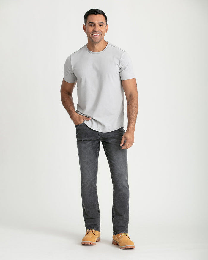 Man wearing light grey t-shirt and grey bootcut jeans with tan work boots.