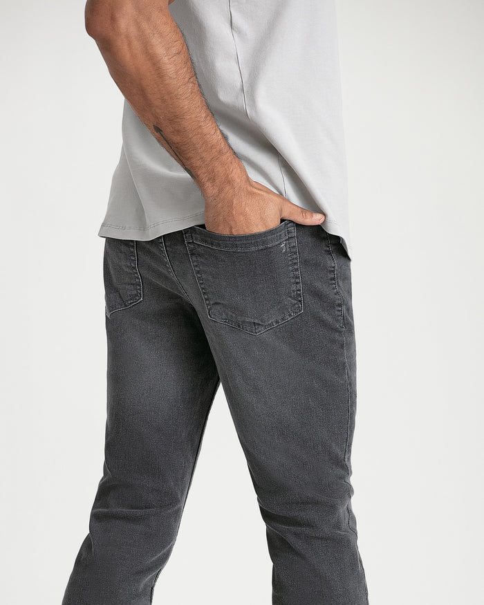 Grey bootcut jeans with five-pocket styling worn with white t-shirt.