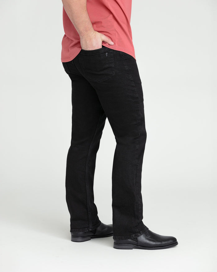 Black bootcut jeans with a slight flare at the hem, shown on a model wearing a pink shirt and black boots.
