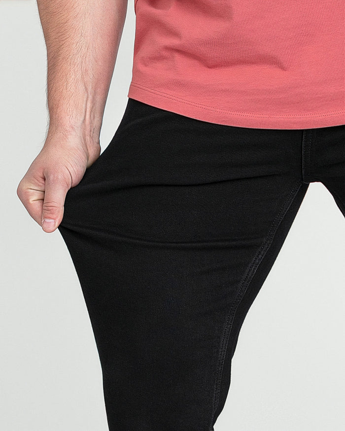 Black bootcut jeans with flared leg opening, shown on male model wearing pink top.