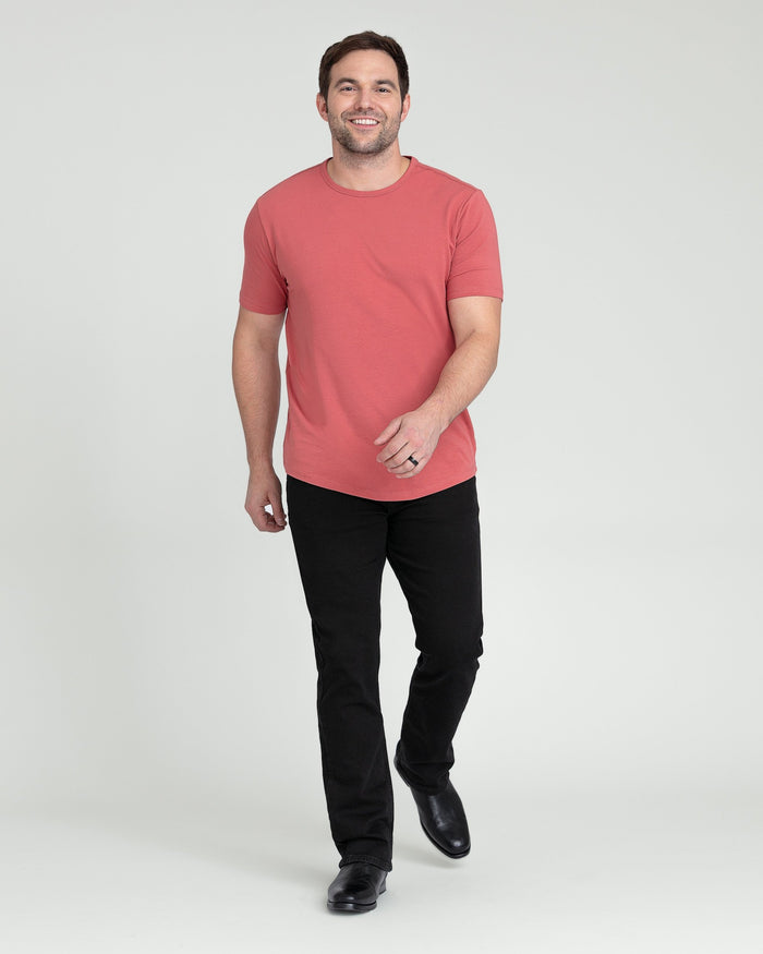 Man wearing coral short-sleeve t-shirt and black bootcut jeans.