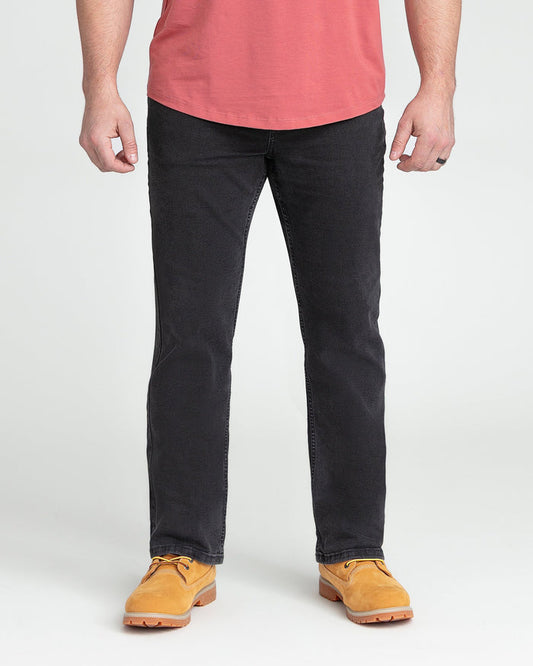Faded black bootcut jeans on model wearing coral t-shirt and tan work boots.