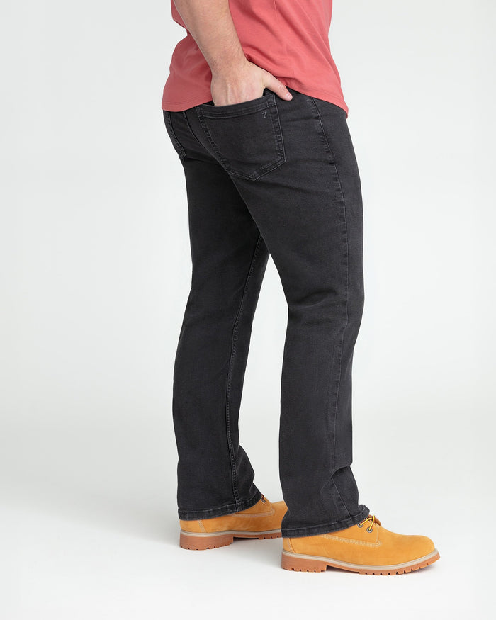Faded black bootcut jeans on model wearing red shirt and tan work boots.