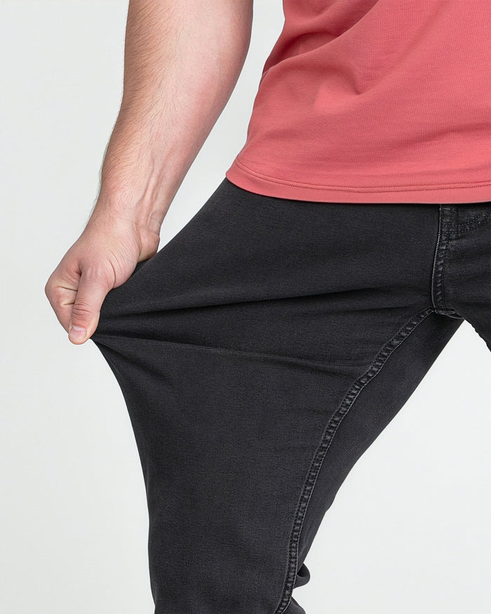 Faded black bootcut jeans on a model wearing a coral-red top, showing the fit from waist to calf.