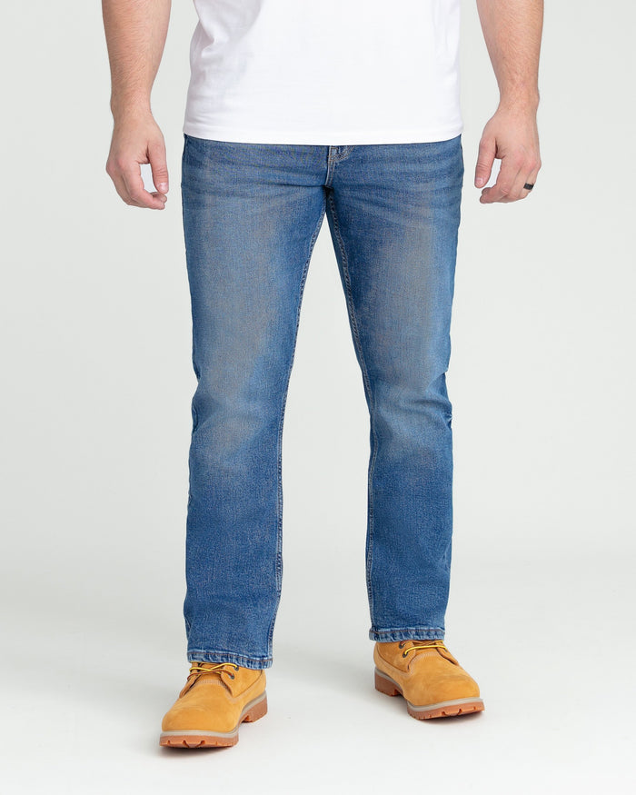 Man wearing medium blue bootcut jeans with white shirt and tan work boots.