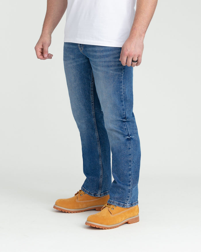 Men's medium blue bootcut jeans with whiskering details on the thighs.