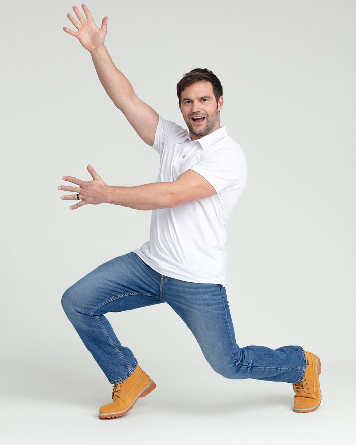 Medium blue bootcut jeans with flared leg opening, shown on model wearing white polo shirt and tan work boots.