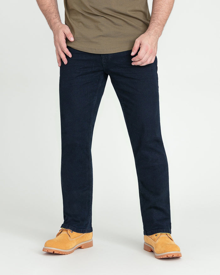 Man wearing deep blue bootcut jeans with tan shirt and tan work boots.
