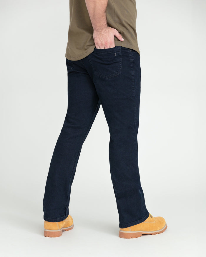 Deep blue bootcut jeans with visible back pocket, worn with tan work boots.